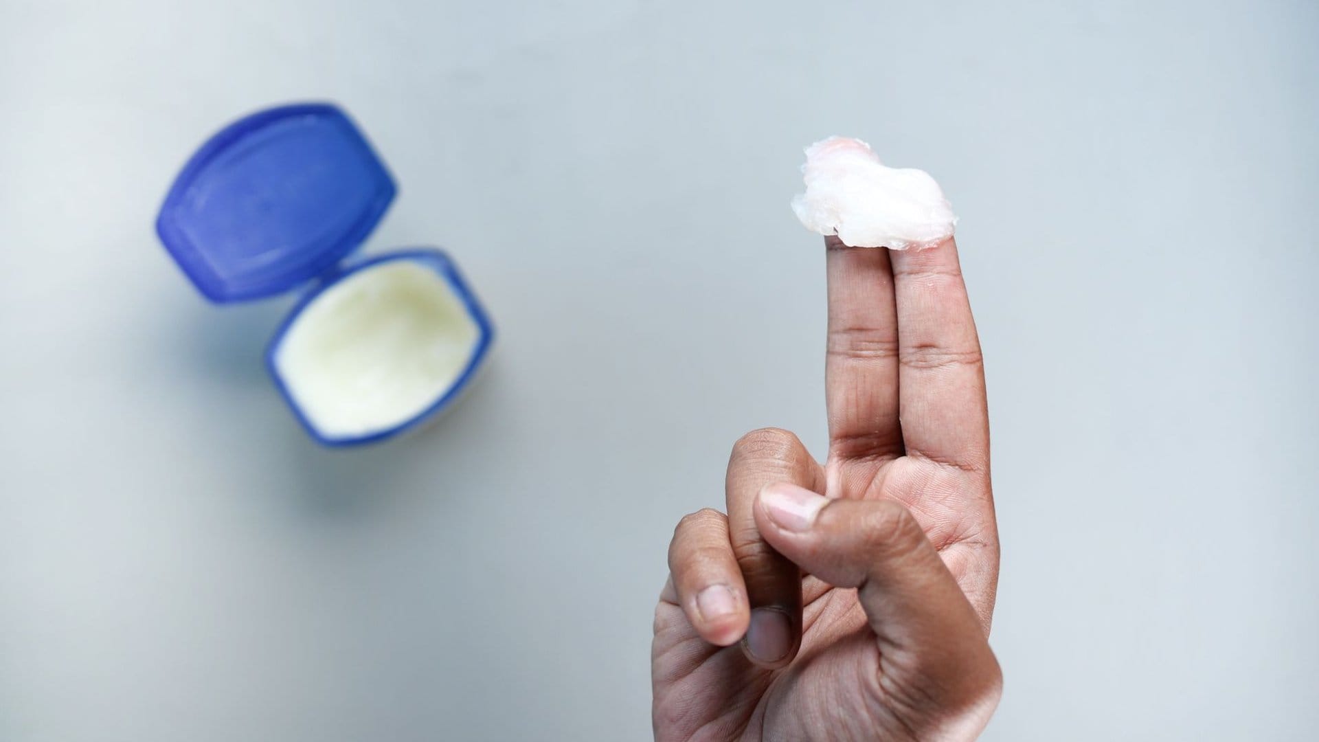 Gleitmittel wird mit dem Finger aus der Dose auf die Fingerspitze aufgetragen, vorbereitet für die Anwendung eines Klysmas