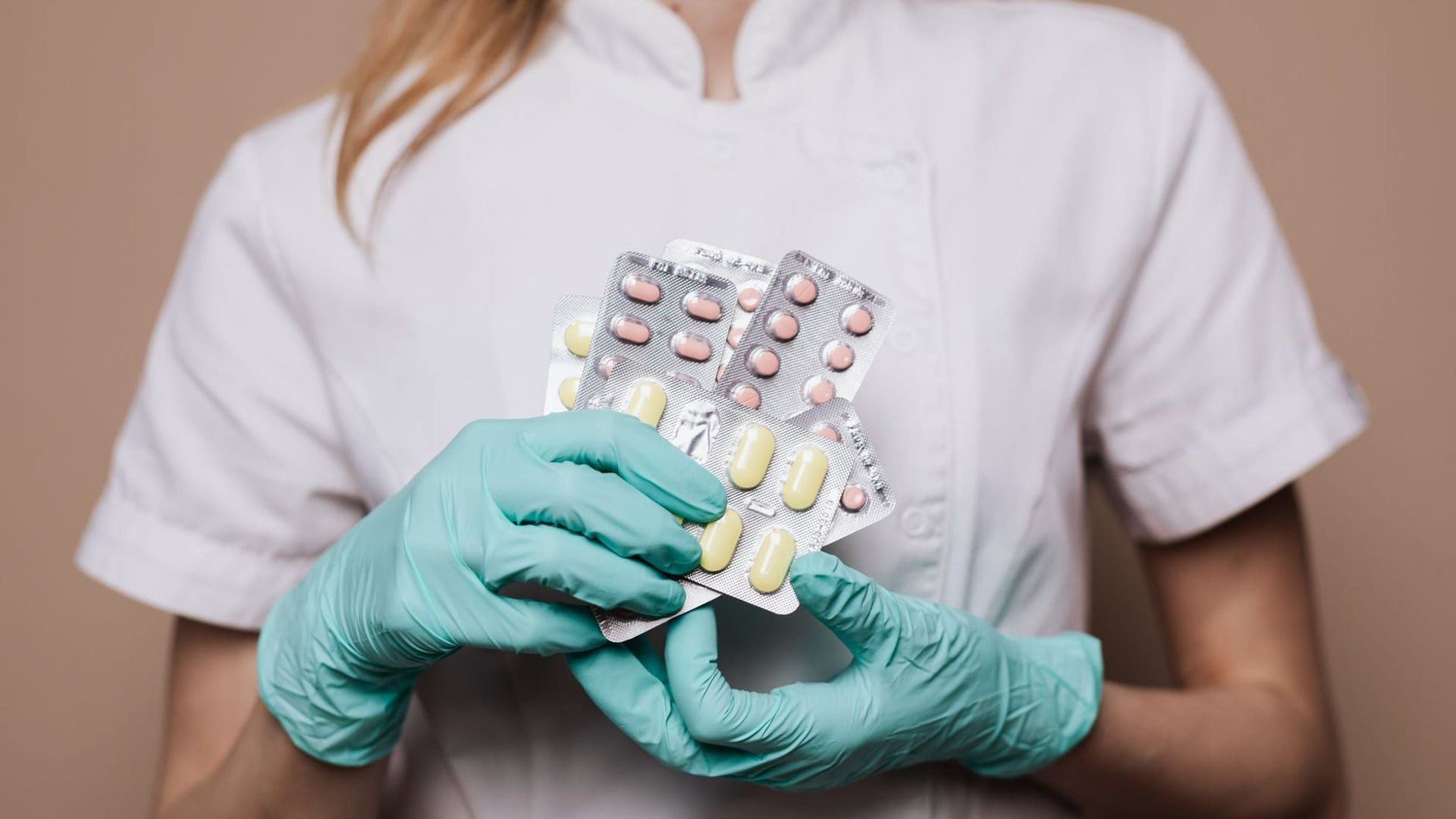Pflegekraft mit Handschuhen hält Medikamentenblister als Symbolbild für den Preisvergleich zwischen Apotheke und Online-Apotheke