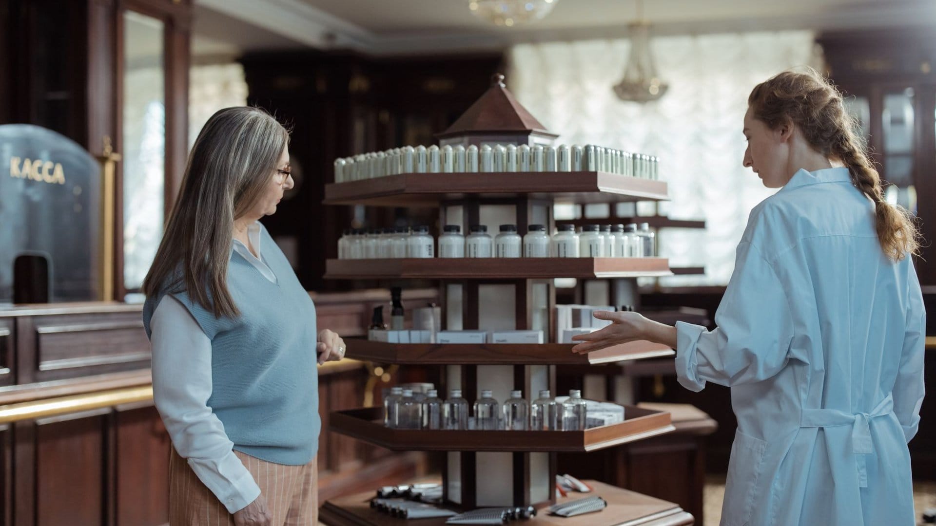 Apothekerin berät eine Kundin vor einem Regal mit Produkten in der Apotheke